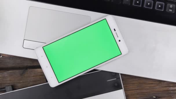 Jeřáb, špičkový telefon se zelenou obrazovkou je na přenosném počítači, na ploše návrháře, fotografka. — Stock video