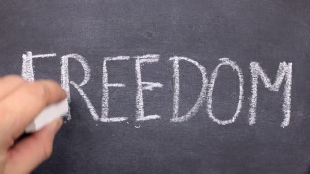 Word FREEDOM, written by hand in chalk on a blackboard. — Stock Video