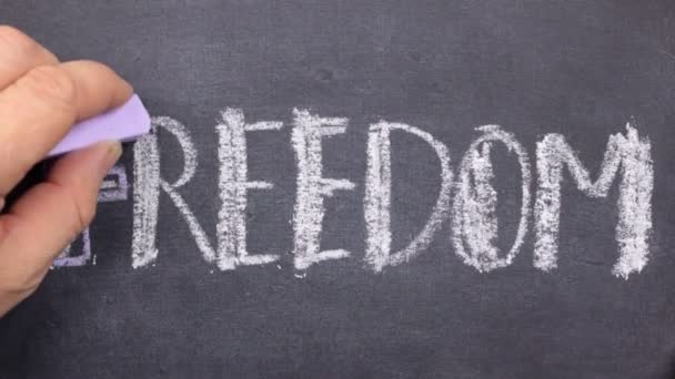 Woord vrijheid, geschreven met de hand in krijt op een schoolbord. — Stockvideo