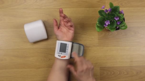 Mâinile femeii, îndepărtați tonometrul din cutie, după măsurarea tensiunii arteriale la masă — Videoclip de stoc
