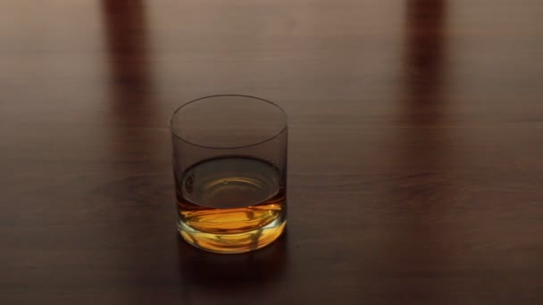 Panorama, glass goblet with whiskey standing on the kitchen table. — Stock Video