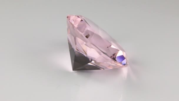 Rotate of a large pink rhinestone on a white background. Beautiful light reflection of a diamond texture. — Stock Video