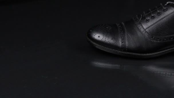 Elegant male shoes with laces stand on a black background with a beautiful reflection. Slider shot. — Stock Video