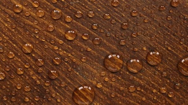 Rotazione di una goccia d'acqua su una bella superficie di legno . — Video Stock