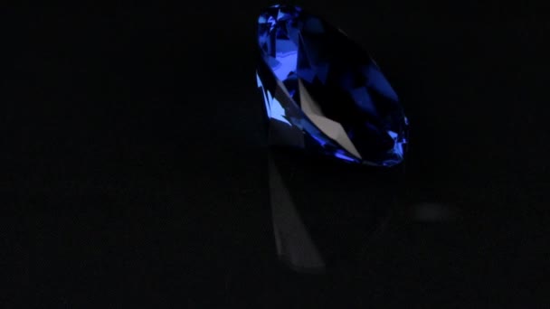 Rotación de un rhinestone transparente azul sobre un fondo negro . — Vídeo de stock