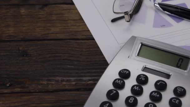 Bureau avec graphiques, lunettes, stylo et calculatrice. Coup de curseur. Entreprises et finances — Video