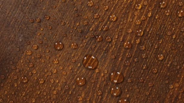 Rotazione di una goccia d'acqua su una bella superficie di legno . — Video Stock