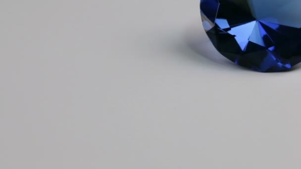 슬라이더 샷, 흰색 배경에 큰 파란색 모조 다이아몬드. 아름다운 빛 반사. — 비디오