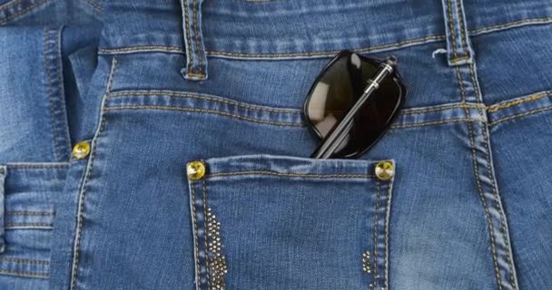 Sunglasses stick out of the back pocket of jeans. Fashion. — Stock Video