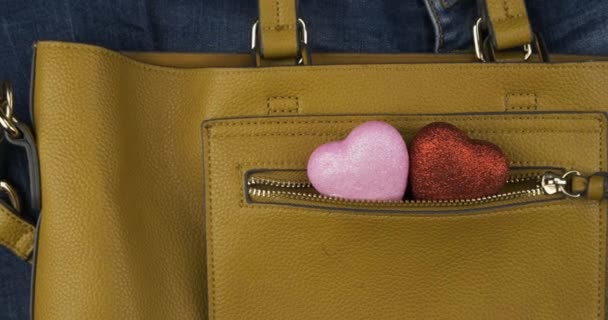 Dos corazones sobresalen del bolsillo de una bolsa femenina. Acercándose, tiro de grúa. Concepto de relación romántica . — Vídeos de Stock