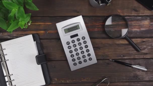 Crane shot. Office desk, focus on the display of a calculator with the number million. Top view. — Stock Video