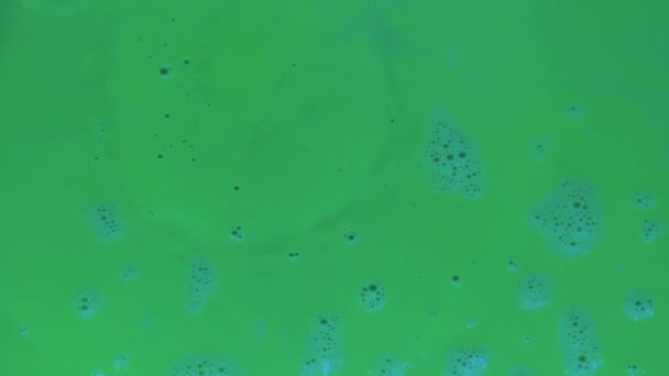 Langzame beweging. Druppels verf vallen in groene fluorescerende verf. — Stockvideo