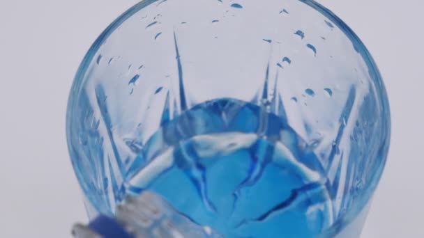 Медленное движение. Вода наливается в стакан на белом фоне. Вид сверху на стакан с пузырьками . — стоковое видео