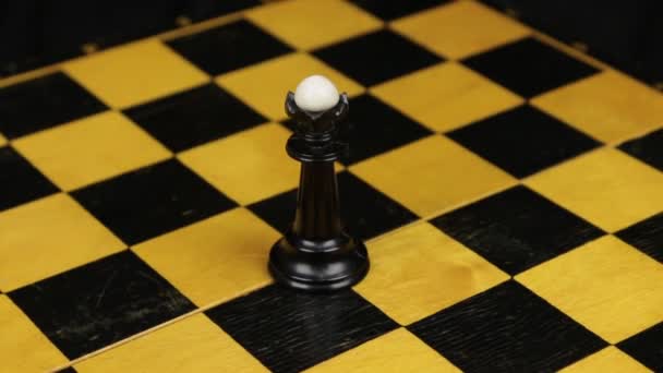 Schach schwarze Dame Figur in der Mitte des Spielbretts in Nahaufnahme. Rotation. — Stockvideo