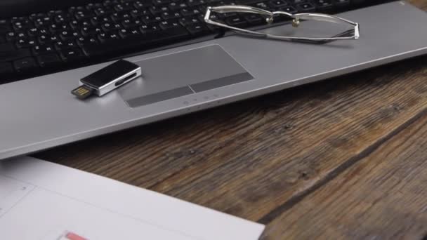 Pracovní stůl. USB flash disk a brýle jsou na notebooku. Snímek posuvníku. — Stock video