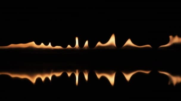 Langzame beweging, pulserend vuur en zijn reflectie op een zwarte achtergrond. — Stockvideo