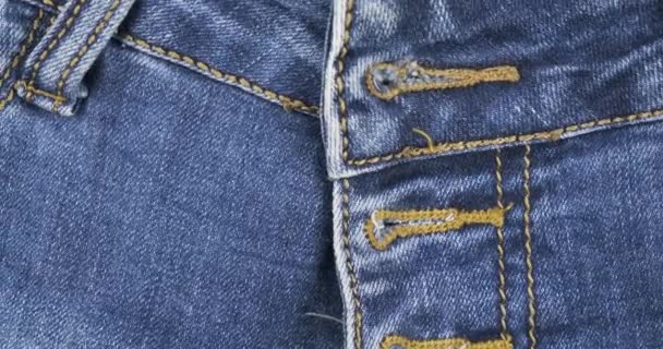 Obrót. Jeansowa faktura, dżinsowe tło. Dziurka w niebieskich dżinsach na pasku w pobliżu zapięcia. — Wideo stockowe
