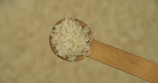 Ложка рисовых зерен поверх вращающихся разбавленных семян риса. Вид сверху. Продукты питания. — стоковое видео