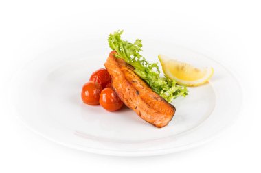 taze salata, domates ve limon beyaz plaka üzerinde kızarmış somon balık