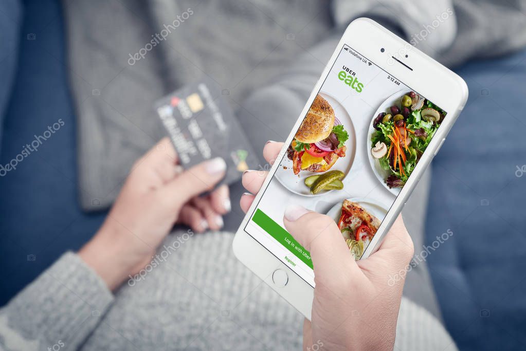 Kyiv, Ukraine - January 24, 2018: Woman using uber eats app on Apple iPhone 8 plus at home for order food delivery