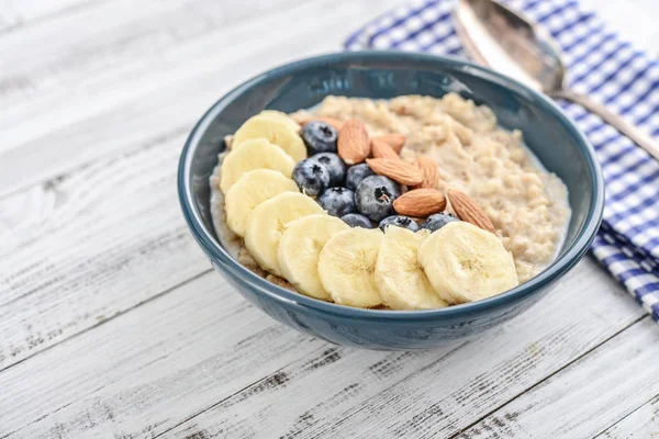 Kom Havermout Havermoutpap Met Banaan Blauwe Bessen Amandelen Houten Achtergrond — Stockfoto