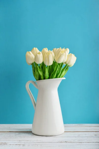白色搪瓷壶白色郁金香花束在蓝色背景 — 图库照片