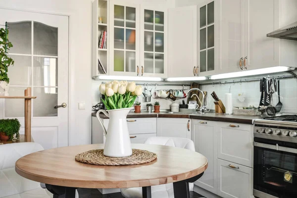 在斯堪的纳维亚风格的厨房内的郁金香花束与白色家具和餐桌 — 图库照片