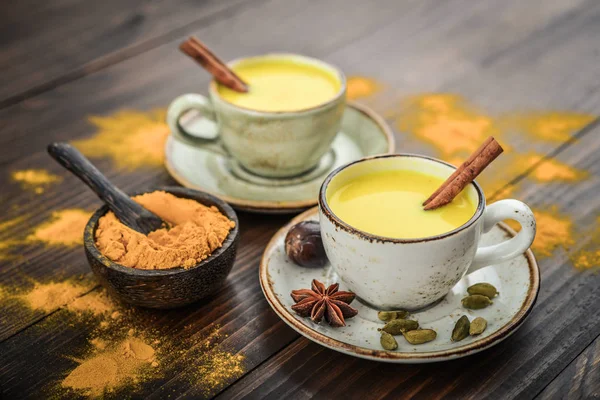 インドの伝統的な飲み物ターメリック ミルクはシナモン クローブ コショウ スパイスと木製の背景でウコン ゴールデン ミルクです — ストック写真