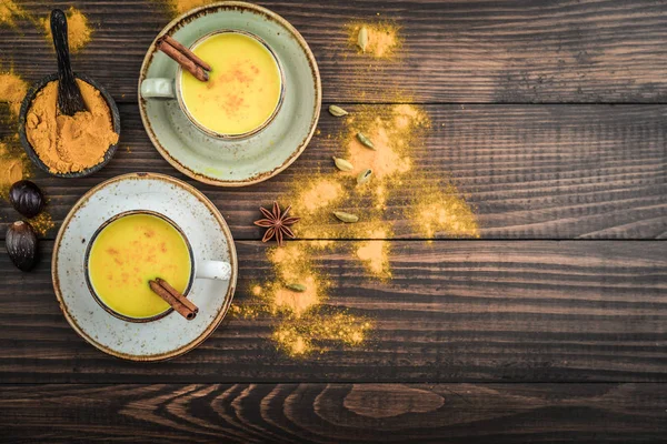 传统的印度饮料姜黄牛奶是金牛奶与肉桂 胡椒和姜黄在木质背景香料 顶部视图 — 图库照片
