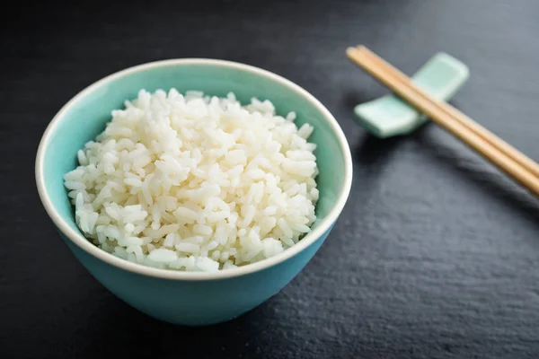 Kokt Ris Skål Och Bambu Ätpinnar Svart Skiffer Bakgrund Närbild — Stockfoto