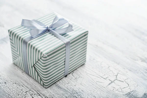 Одна Полосатая Подарочная Коробка Серой Лентой Белом Деревянном Фоне Closeu — стоковое фото