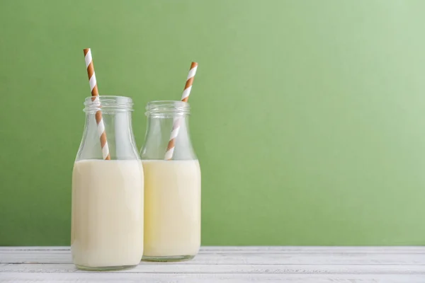 两瓶牛奶和喝吸管在绿色背景 — 图库照片