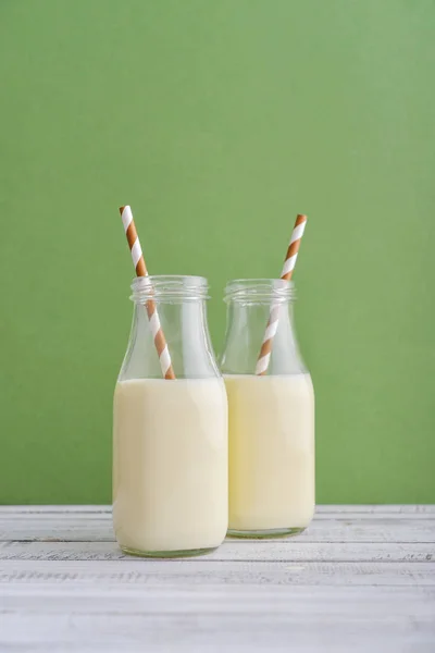 Zwei Flaschen Mit Milch Und Trinkhalmen Auf Grünem Hintergrund — Stockfoto