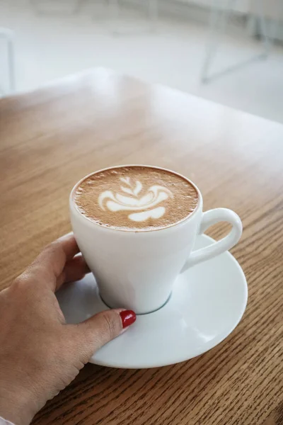 La mano femenina sostiene una taza de capuchino —  Fotos de Stock