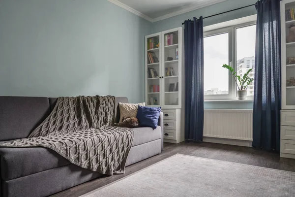 明るい居心地の良い10代のお部屋に白い本棚 グレーのソファ 青い壁 — ストック写真