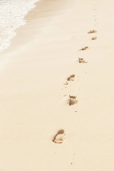 Imprint of human feet on the beach sand near the water shore