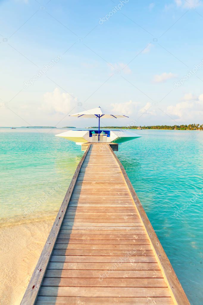 Wooden pier, jetty at tropical island resort in early morning, Maldives. Vacations And Tourism Concept