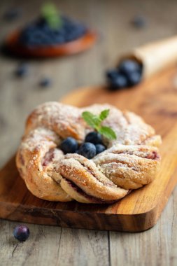 Yaban mersinli çörek pudra şekeri ve ahşap tahta üzerinde taze çilek ile pileli. Dikey kompozisyon.