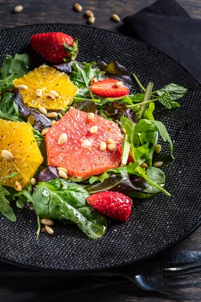 Salat Mit Grapefruit Orange Erdbeere Und Pinienkernen Auf Schwarzem Teller — Stockfoto
