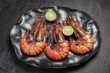 Karanlık tabakta yemek için üç jumbo karides. Gıda arka plan. Üstten görünüm.   
