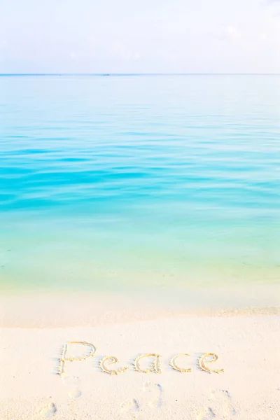 朝海背景でビーチの砂に書かれた単語平和 — ストック写真