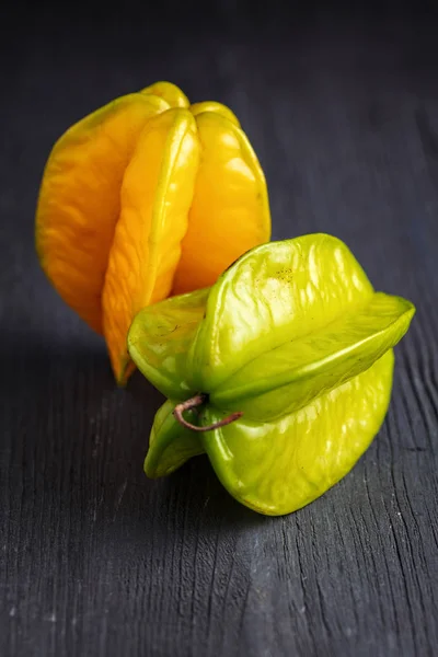 ripe yellow and green star fruit carambola or star apple ( starfruit ) on dark wooden background
