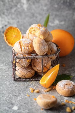Ev yapımı turuncu grup Krinkıl çerezleri pudra şekeri ile taze portakal, dikey kompozisyon gri arka plan üzerinde küçük metal sepet içinde krema ile