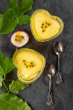 İki kalp şeklinde ramekin ile tutku meyve mus koyu arka plan, üstten görünüm, dikey kompozisyon