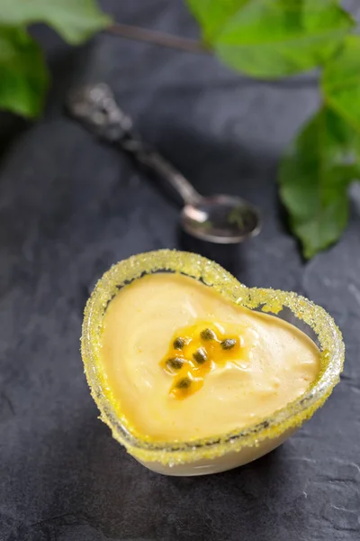 Passionsfrukt mousse i hjärtformat glas ramekin på mörk bakgrund, ovanifrån, vertikala sammansättning — Stockfoto