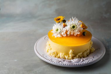 Çiçek ve gri arka plan üzerinde taze mango adet ile sırlı Mango cheesecake  