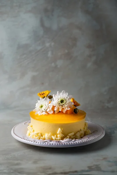 釉面芒果芝士蛋糕与花和新鲜芒果片在灰色背景 垂直构成 — 图库照片