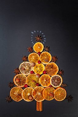 Noel ağacının kurutulmuş portakal, tarçın ve anasonu koyu arka plan üzerinde yapılmış. Yukarıdan izlendi.