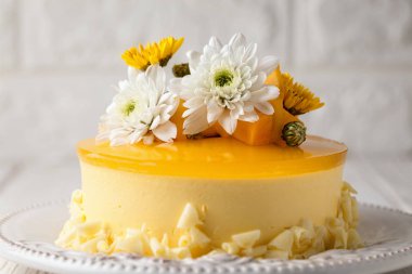 Beyaz ve sarı çiçek ve gri arka plan, yatay kompozisyon üzerinde taze mango adet ile sırlı Mango cheesecake