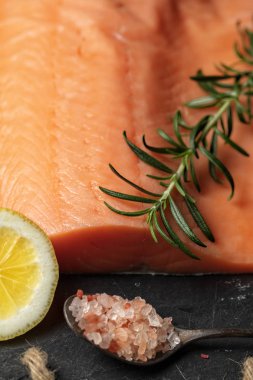 Siyah arduvaz levha ve malzemeler gravlax yapmak için çiğ somon fileto. Tuz, şeker, limon ve biberiye kuru tedavi için arka planda, koyu arka plan, dikey kompozisyon Marine 